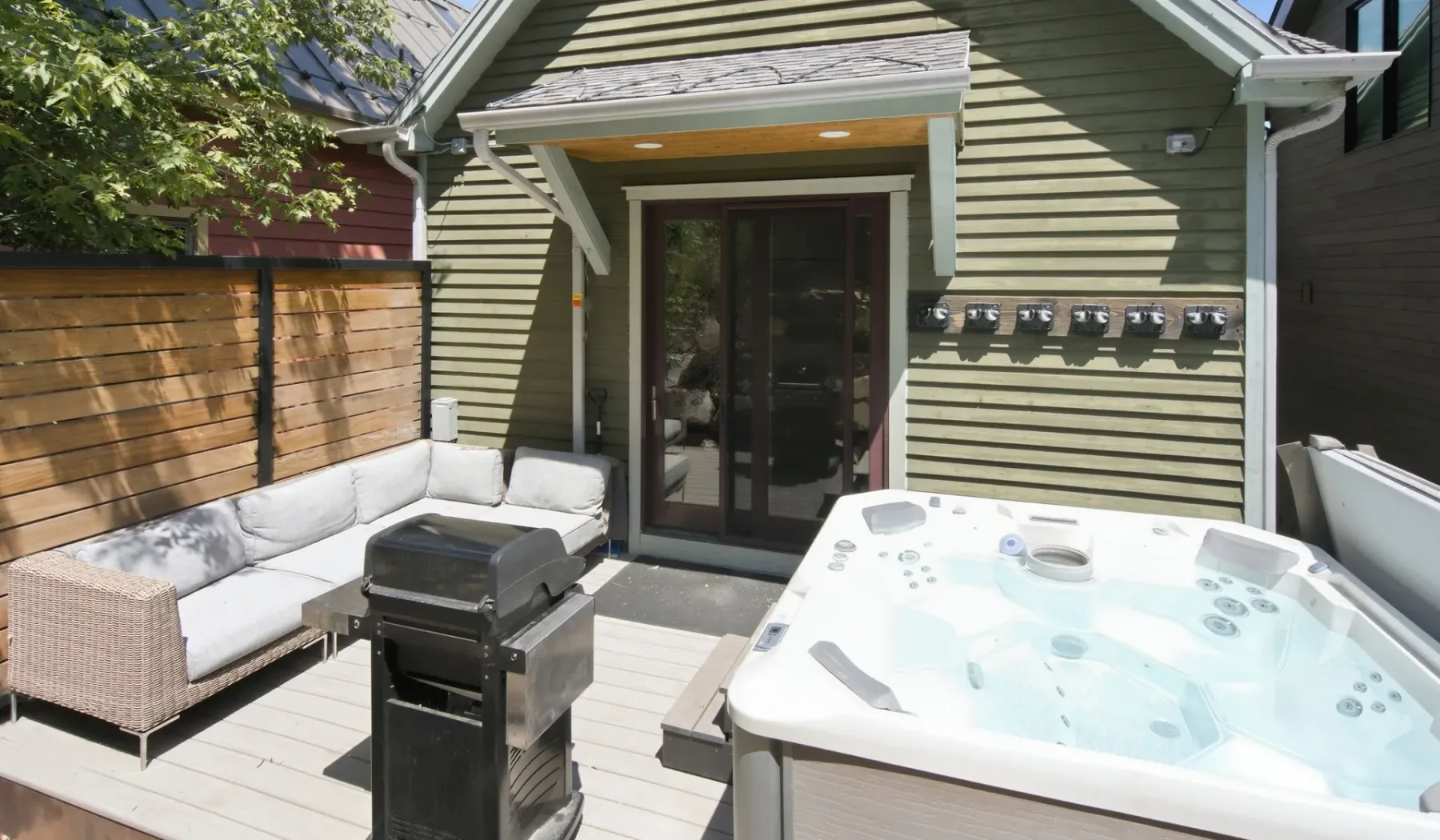 Un patio con jacuzzi, parrilla y asientos al aire libre junto a una casa.
