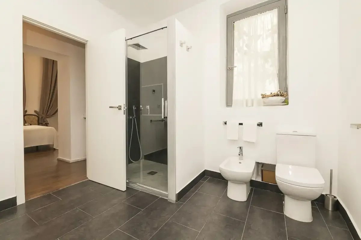 A bathroom with a glass shower, sink, and toilet.