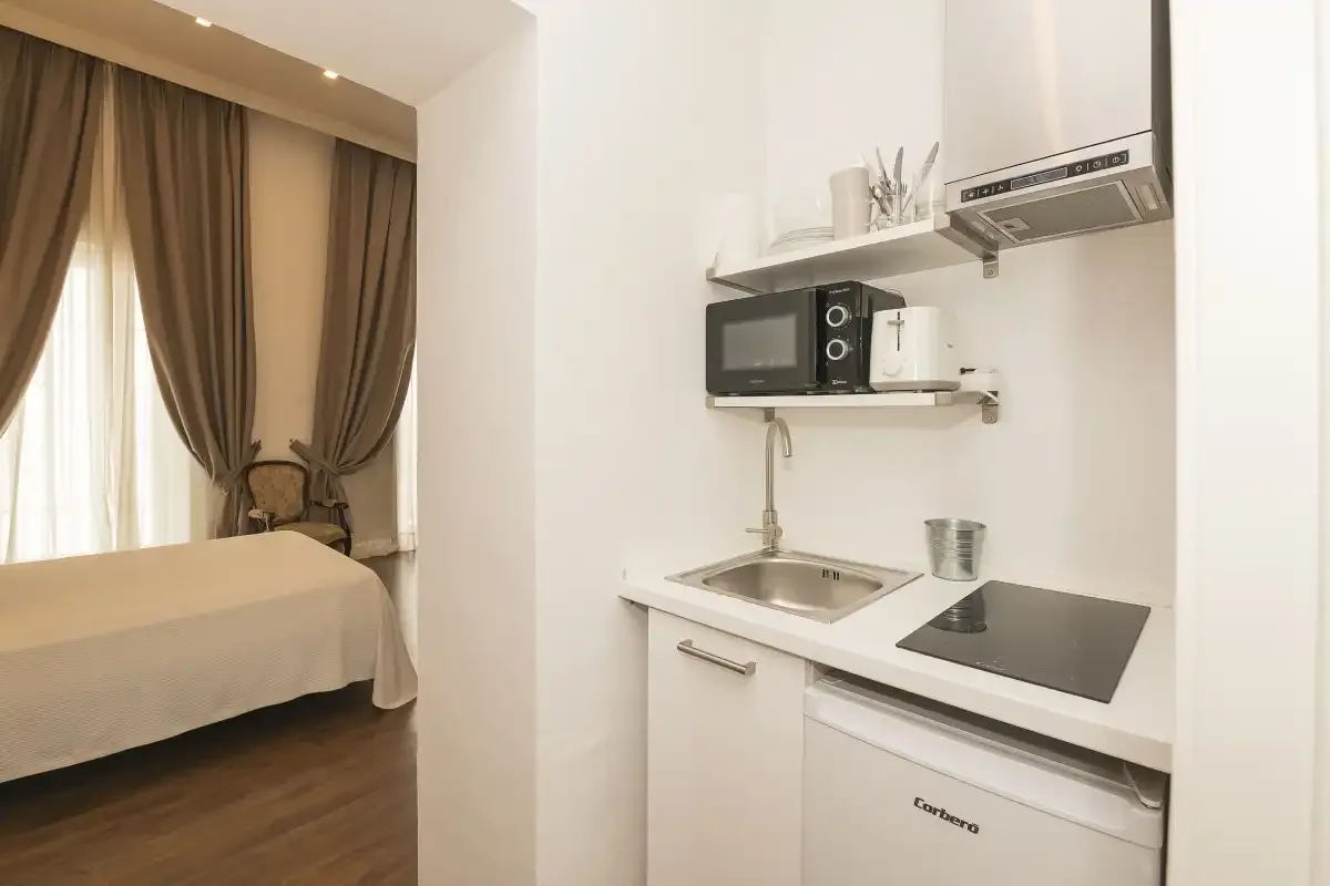 A compact kitchenette with a sink and cooktop sits beside a curtained sleeping area.