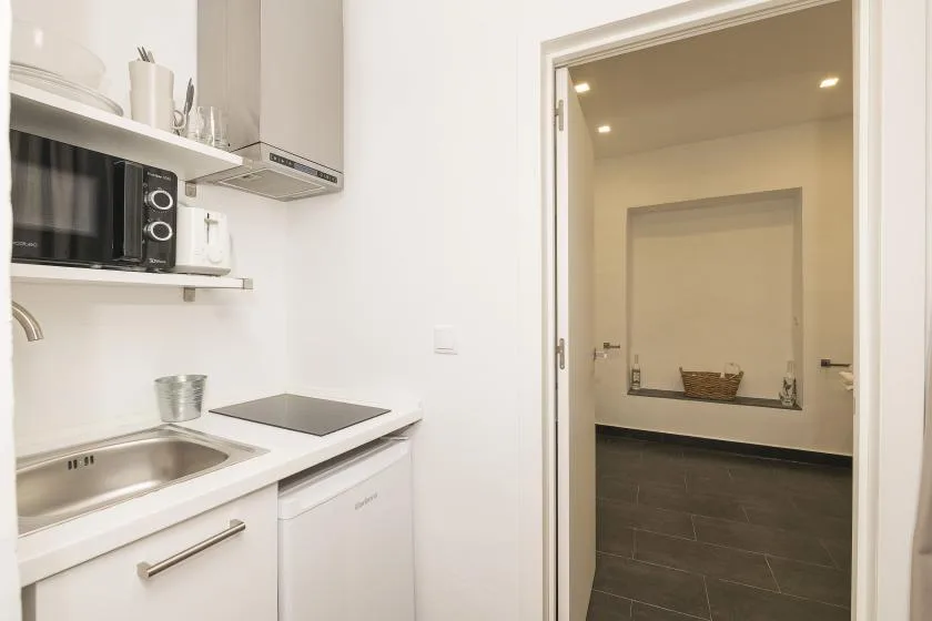 A compact kitchen opens onto a tiled hallway.