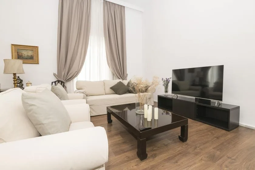 A bright living room with seating arranged around a coffee table and television.