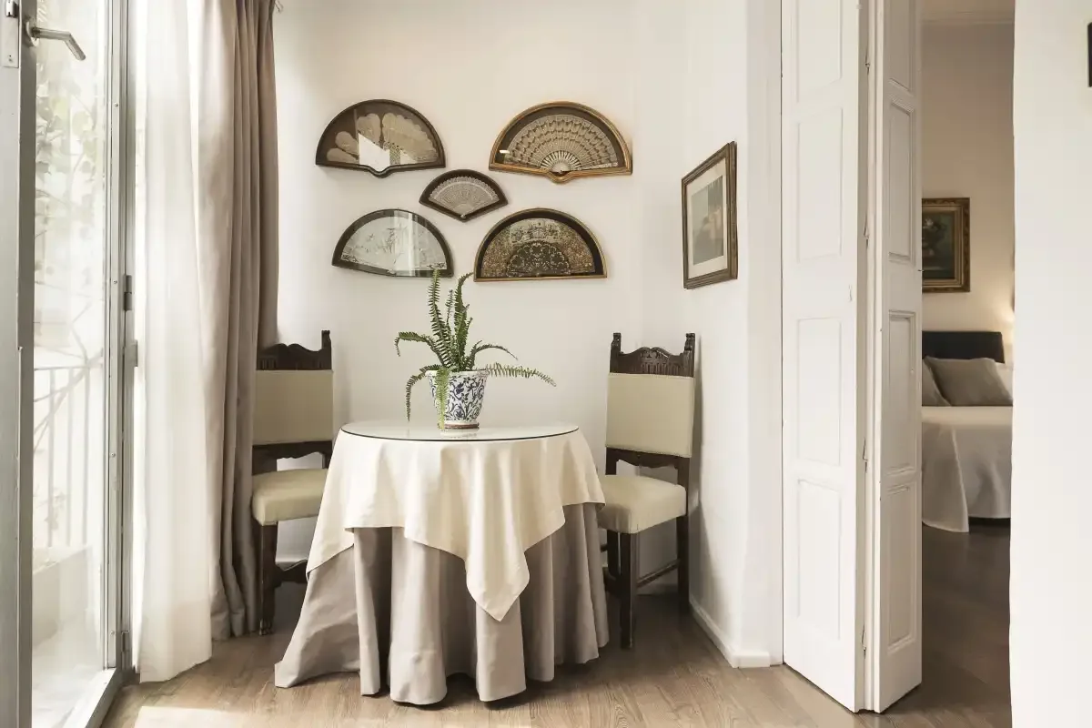 A dining area with a round table, chairs, and decorative fans on the wall.