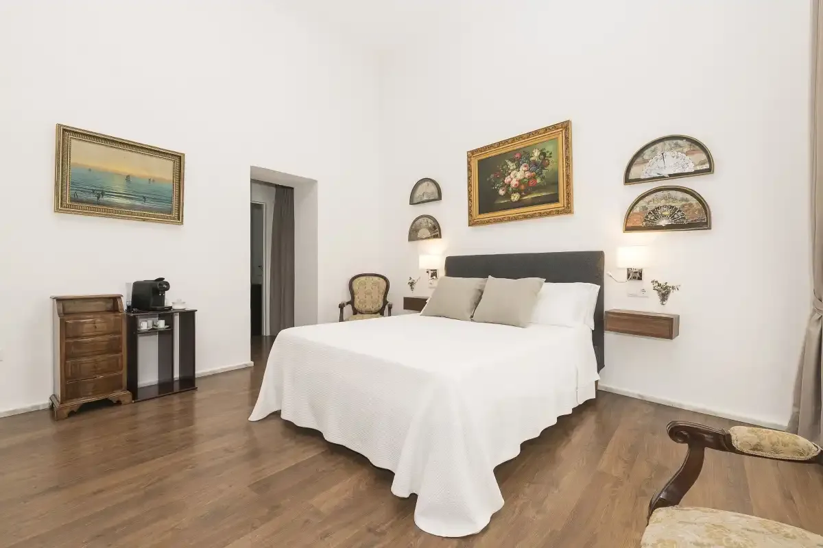 A bedroom with a neatly made bed and framed artwork on the walls.