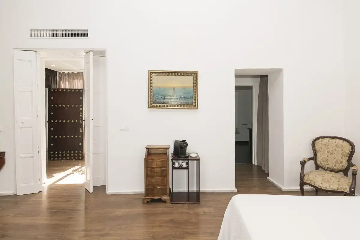 A bedroom with a bed, a framed picture, and an open doorway.