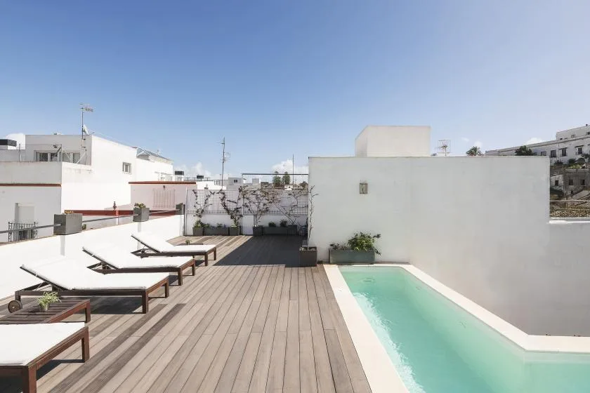 A rooftop terrace with a swimming pool and wooden deck.