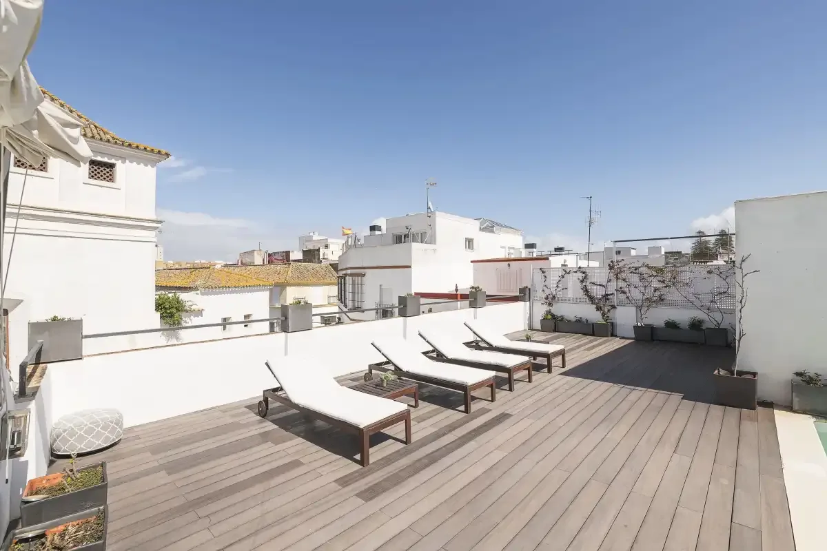 A rooftop terrace with loungers and a wooden deck.
