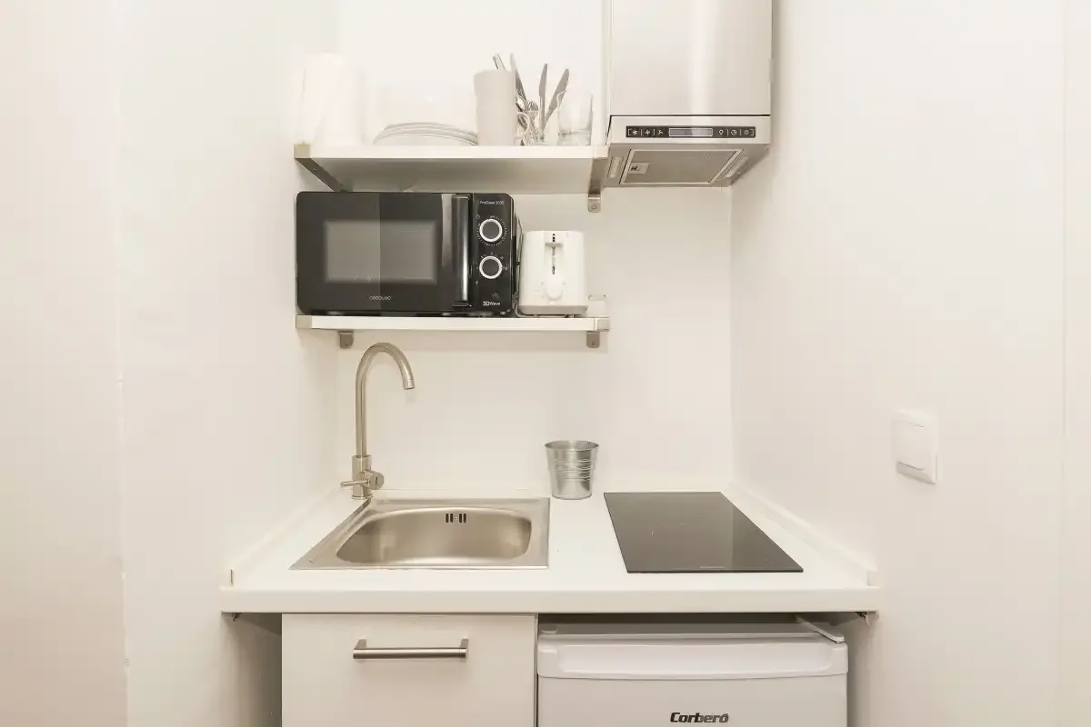 A compact kitchen with a sink, microwave, and cooktop.