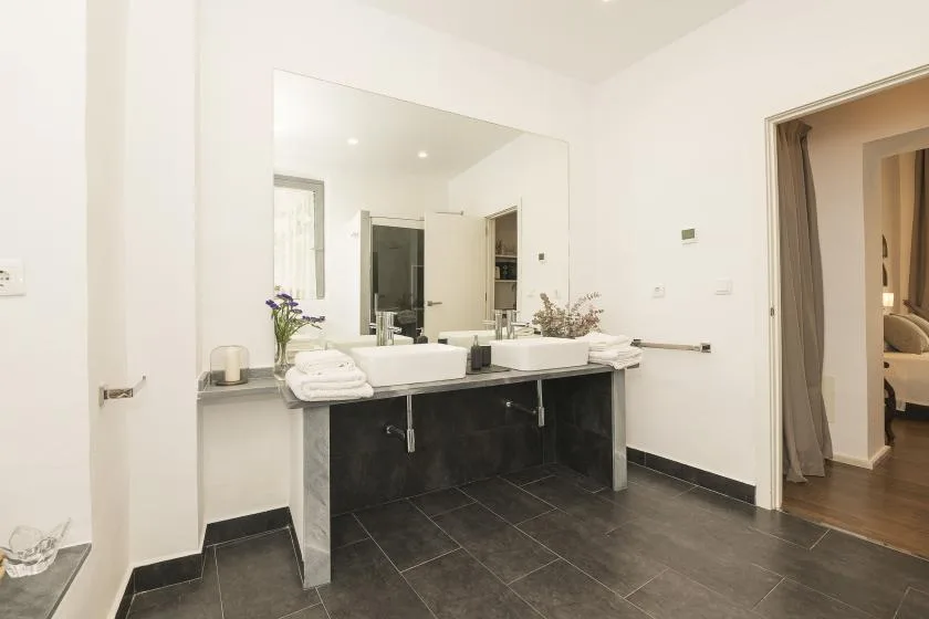 A bright bathroom with a double-sink vanity and large wall mirror.