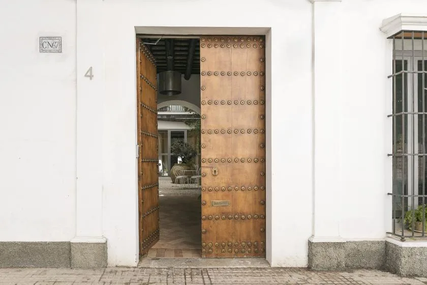 A white building entrance with a large open wooden door.