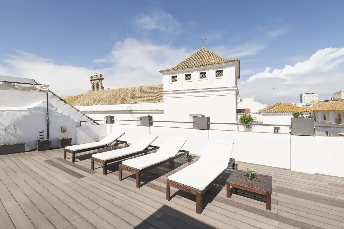 A rooftop terrace with lounge seating and a view of nearby buildings.