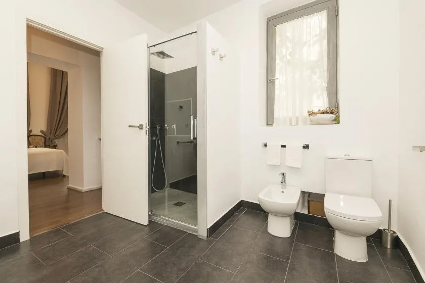 A bright bathroom with a glass shower, sink, and toilet.