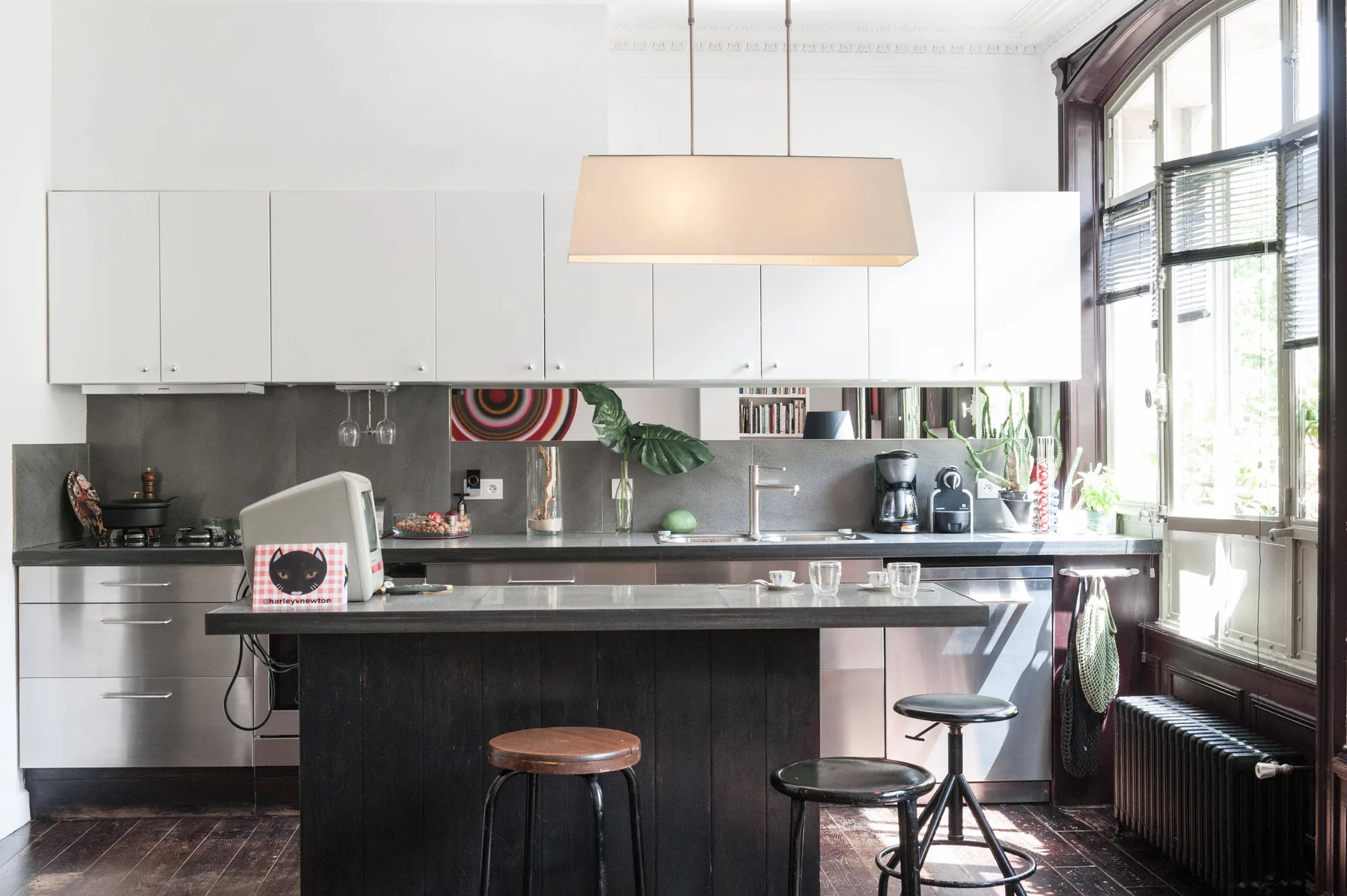 A bright kitchen with a dark island, white cabinets, and large windows.