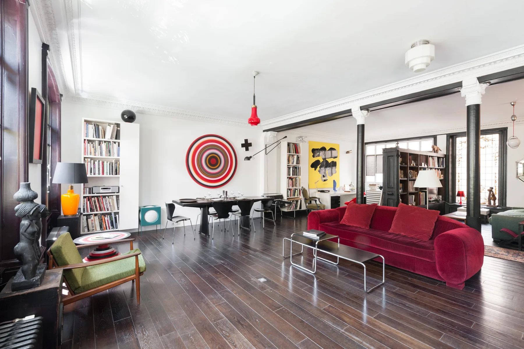 A living room with red seating and a large circular wall decoration.