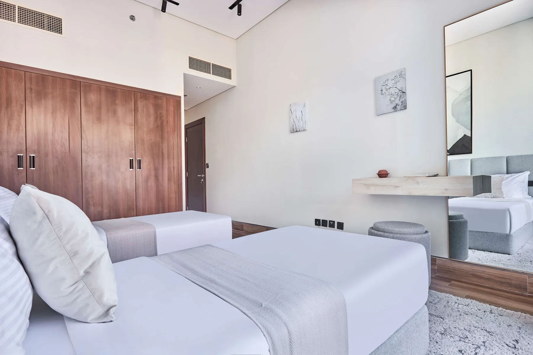 A bedroom with neatly made beds and a large wooden wardrobe.