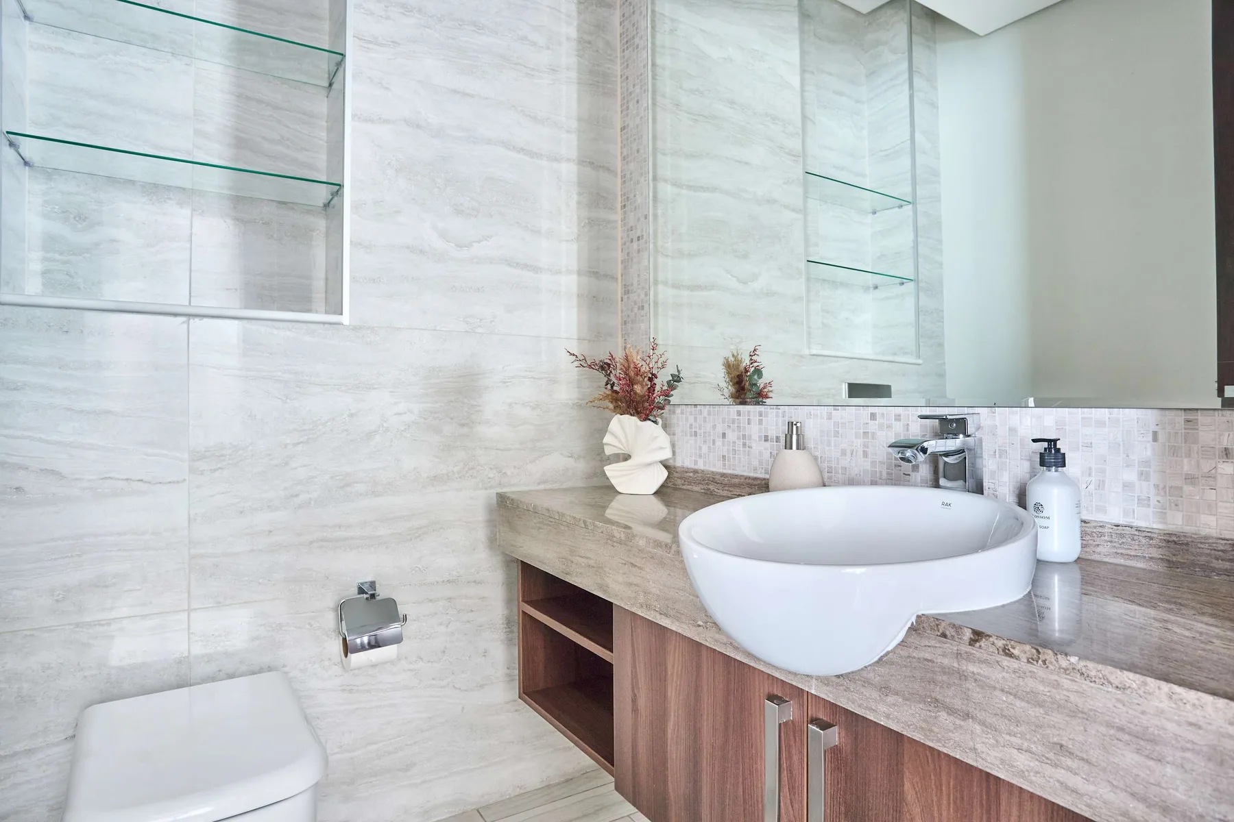 A bright bathroom with a vessel sink, stone countertop, and tiled walls.
