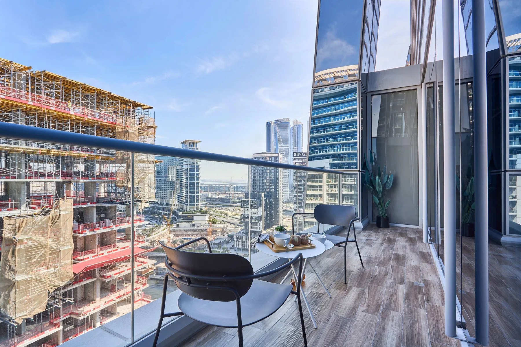 A balcony seating area overlooks nearby high-rise buildings and construction.