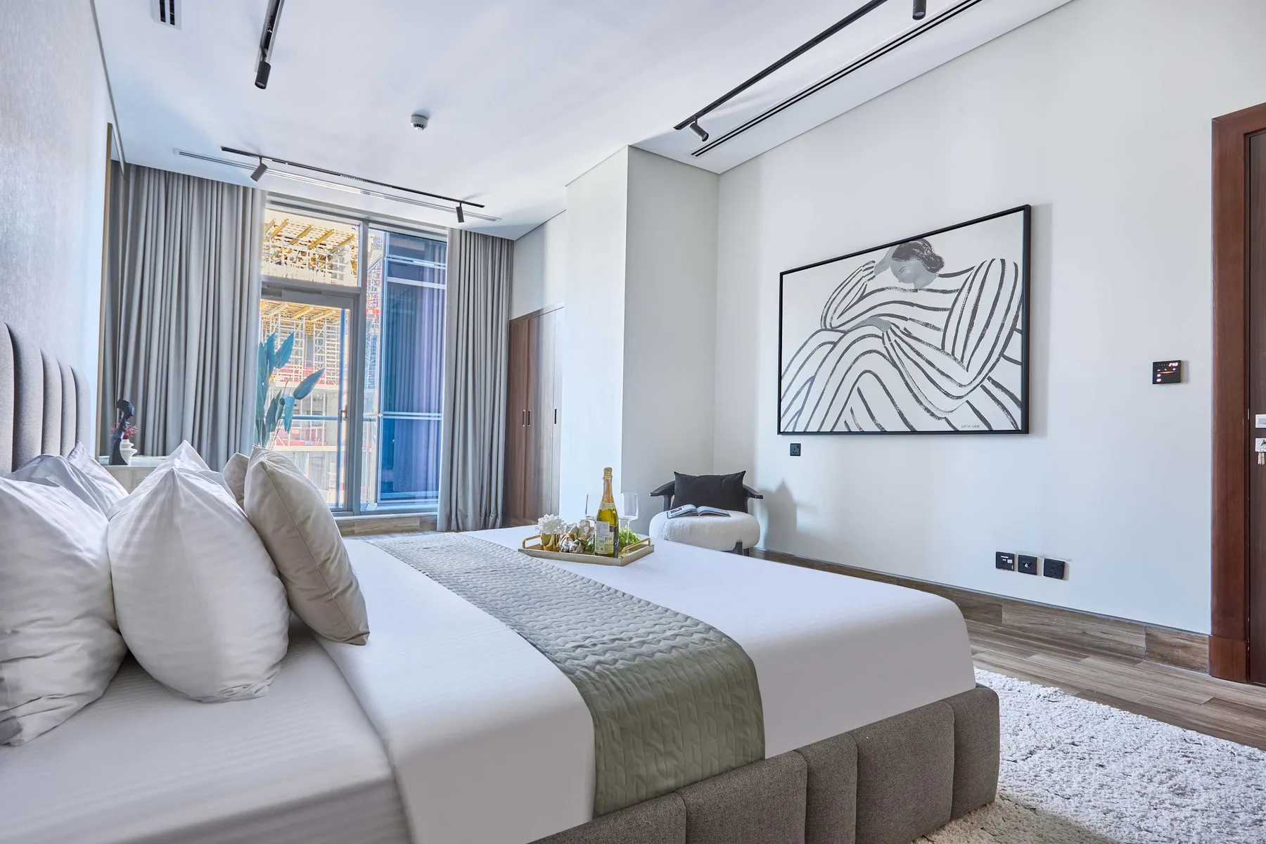 A bright bedroom with a bed, gray curtains, and framed wall art.