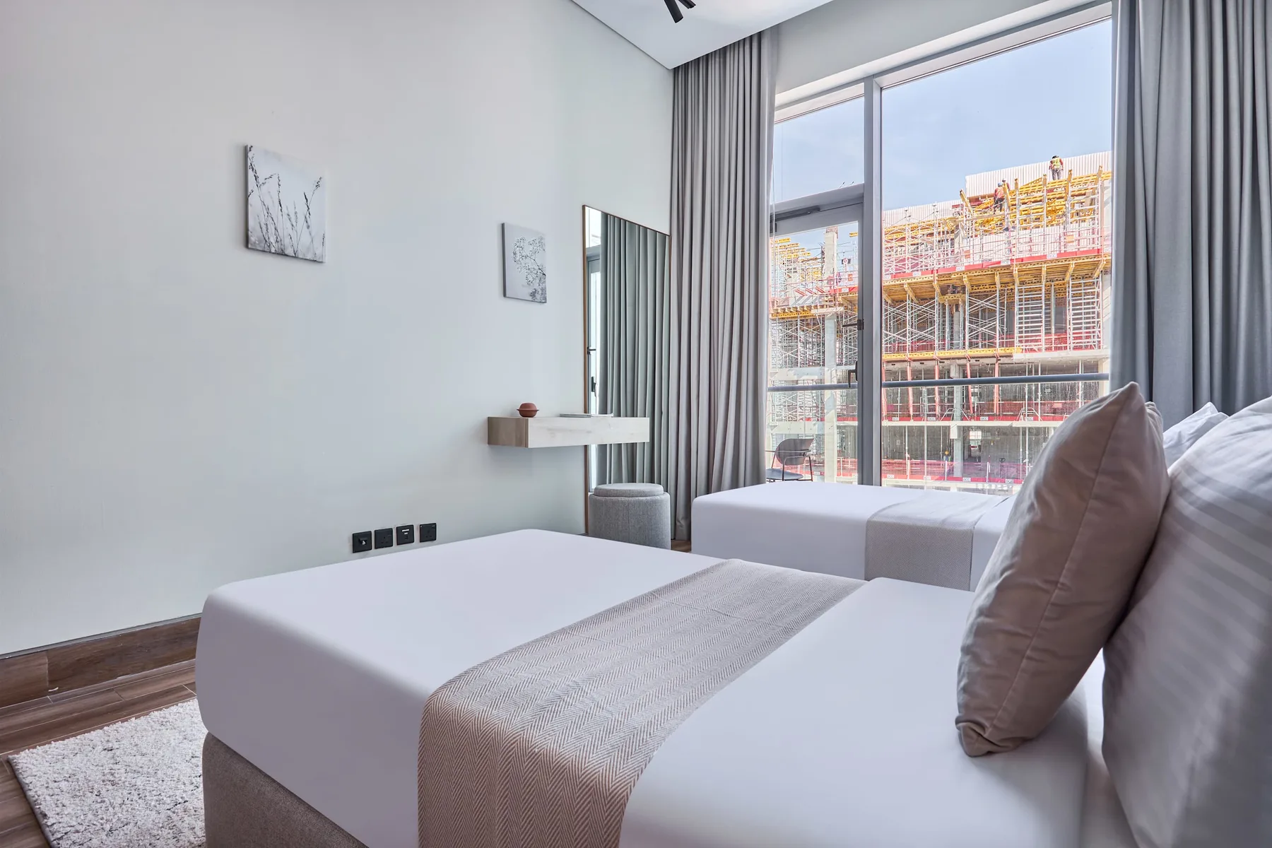 A bright bedroom with white bedding and floor-to-ceiling windows.