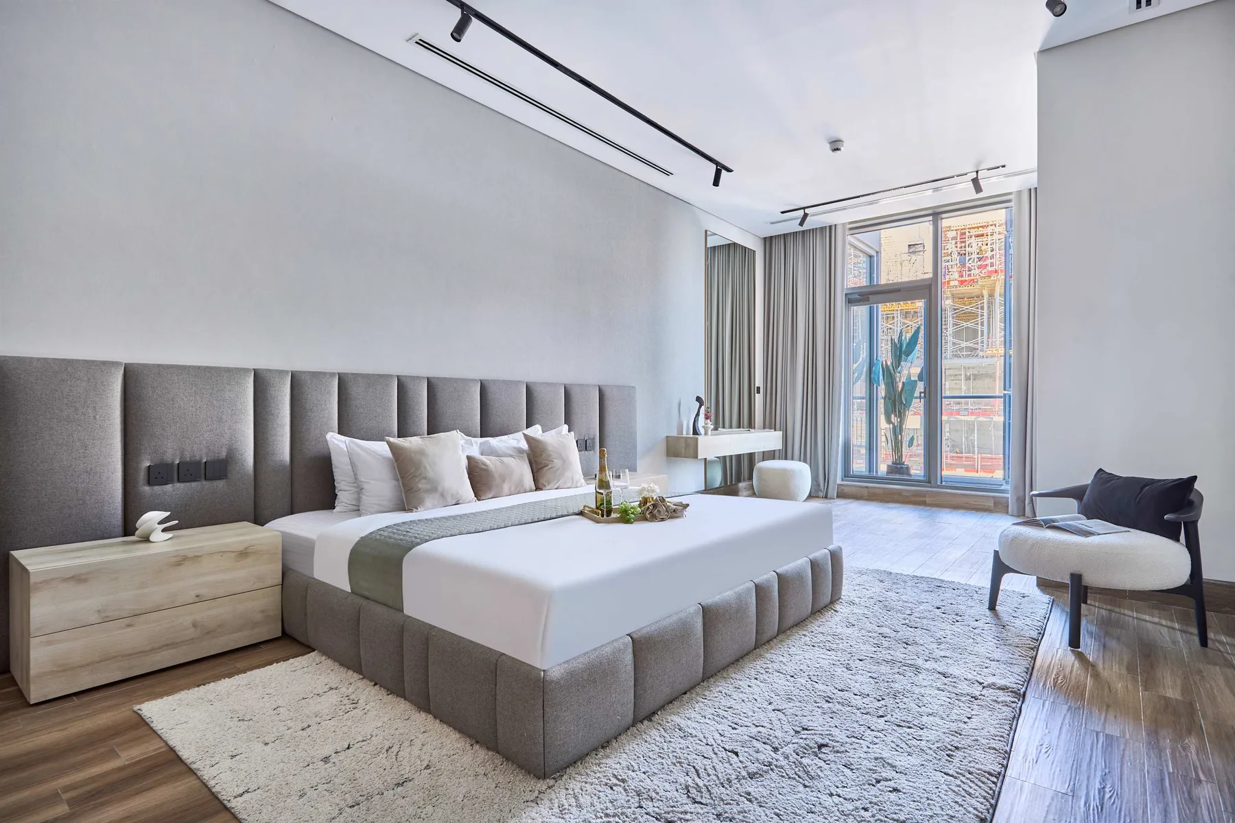 Dormitorio con una cama grande, una mesita de noche y ventanas altas.