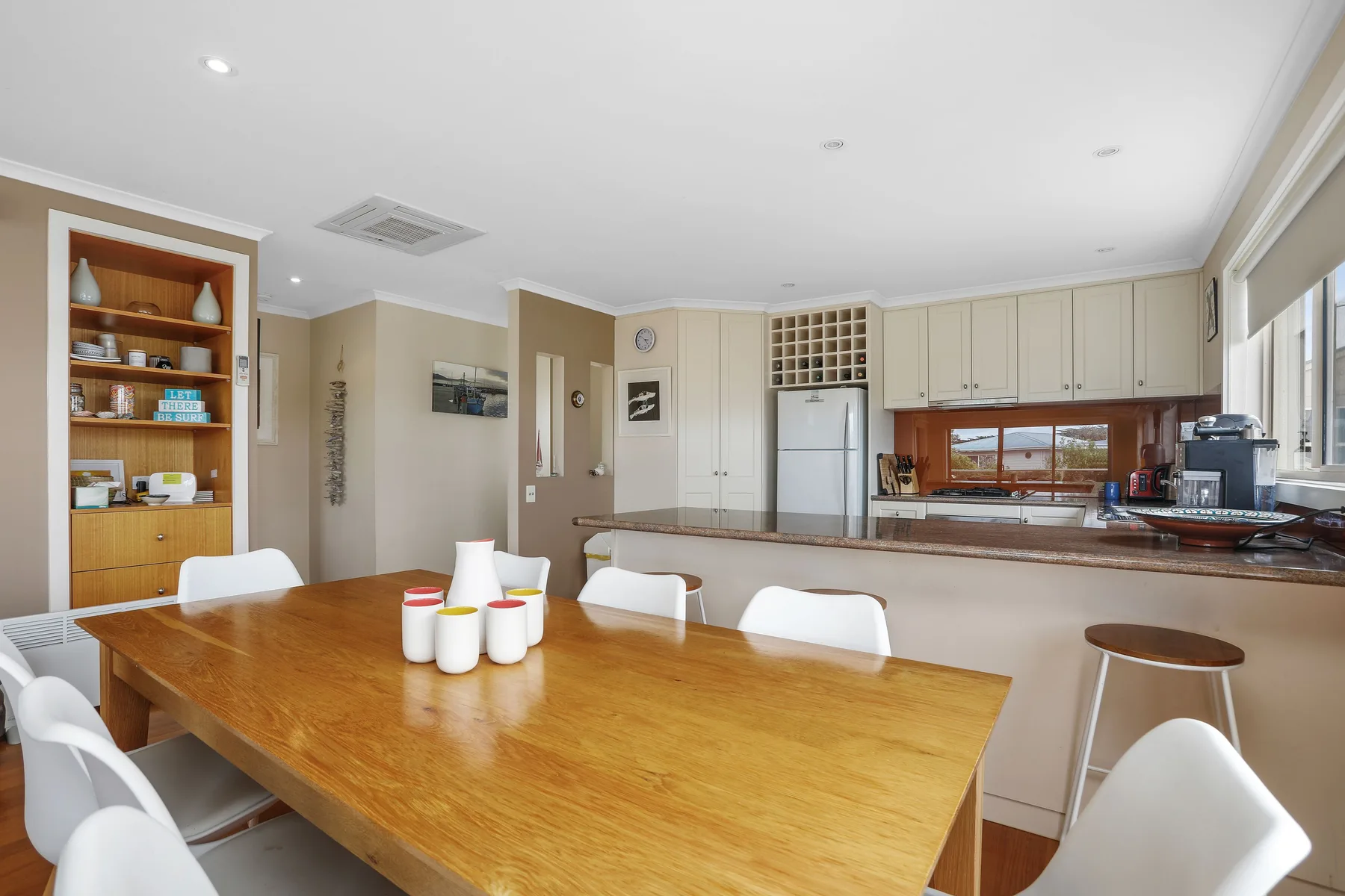 A dining area with a wooden table beside an open kitchen.