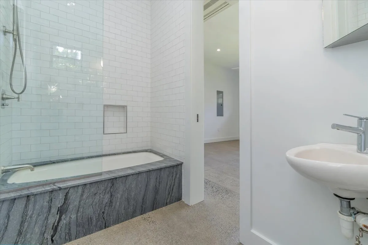 A bright bathroom with a tiled bathtub and a wall-mounted sink.