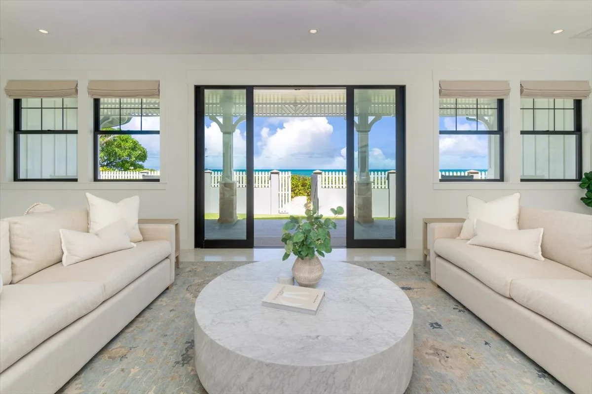 A bright living room with seating and a round coffee table facing glass doors.
