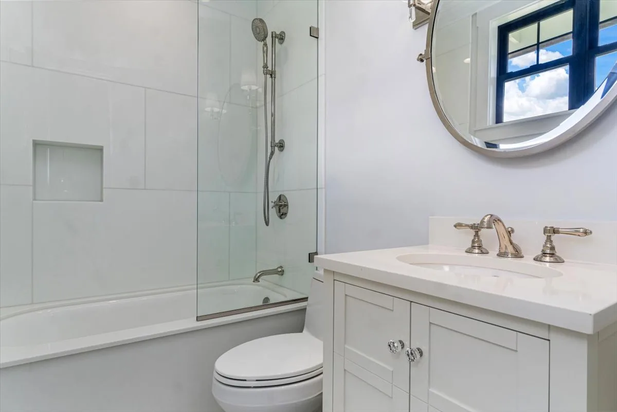 A bright bathroom with a bathtub, shower, toilet, and vanity.
