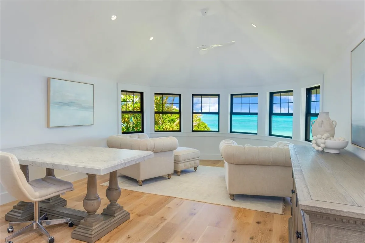A bright living room with seating arranged around large windows overlooking the water.