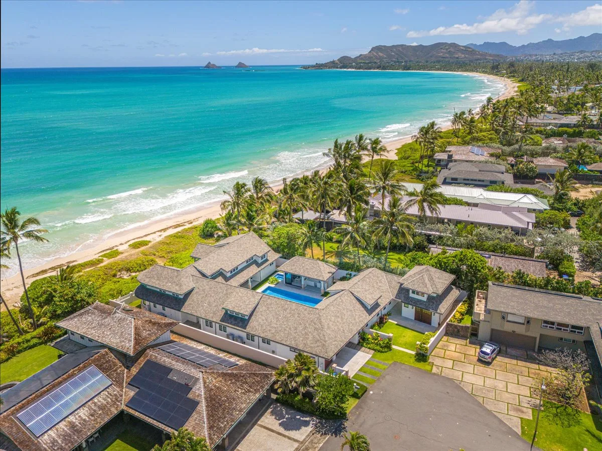 Aerial view of a coastal resort beside a turquoise bay and palm-lined beach.