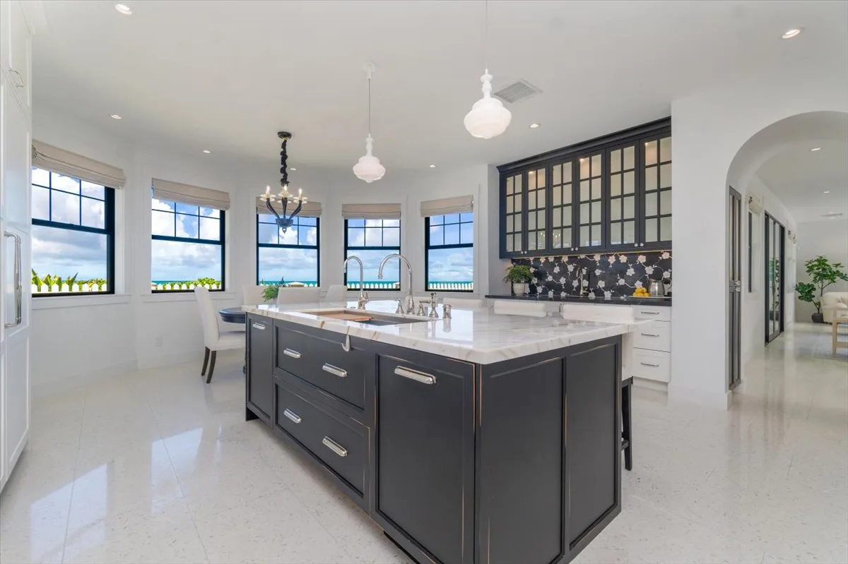 A bright kitchen with a large central island and several windows.