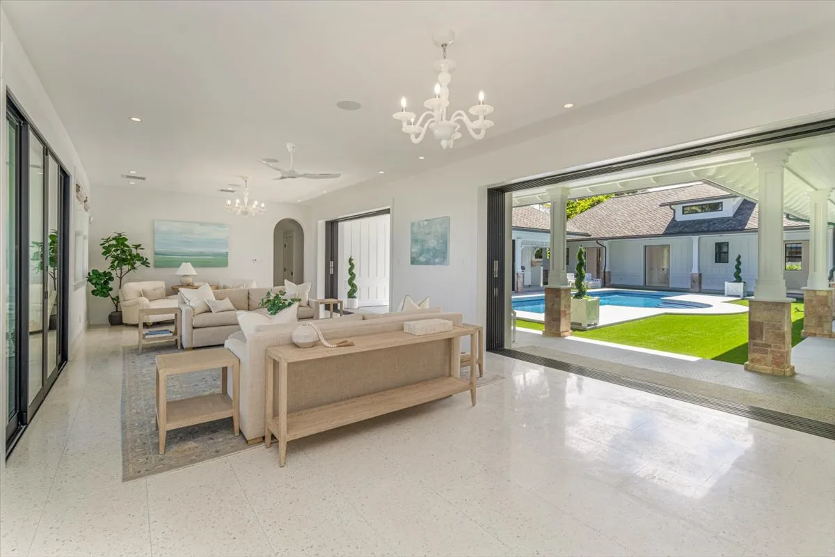 A bright living room opens onto a pool courtyard through wide glass doors.