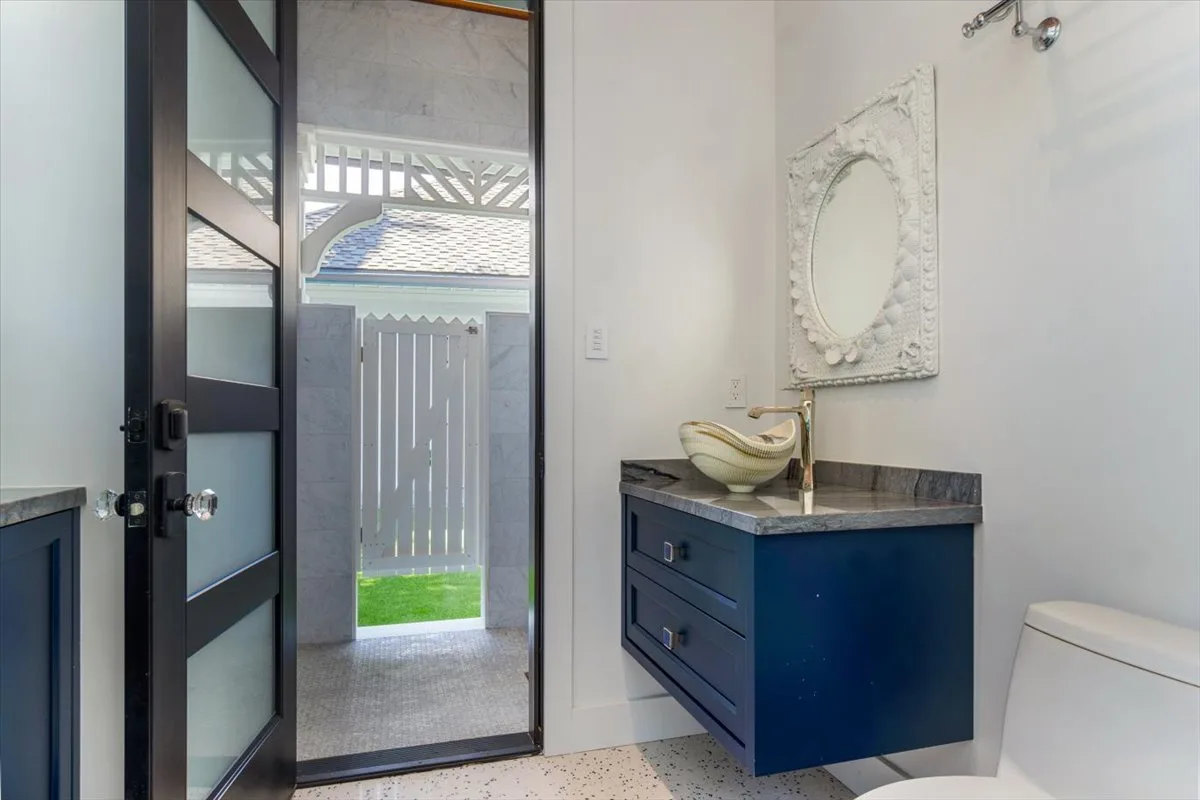 A bathroom with a floating vanity, decorative mirror, and an open doorway.