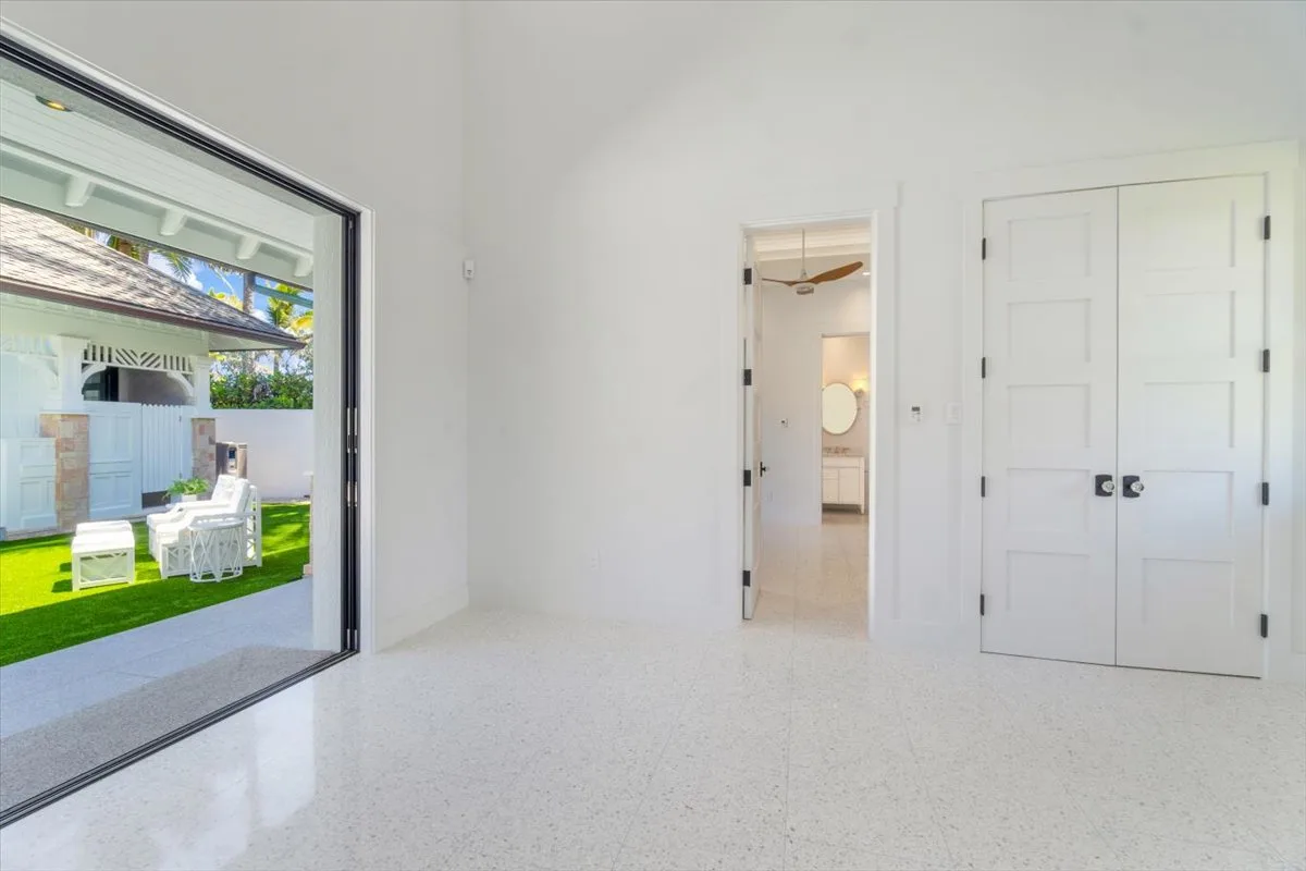 A bright interior room with a wide glass door opening onto a patio and lawn.
