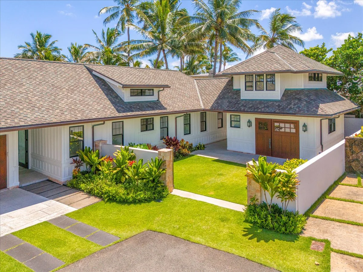 A light-colored house with a landscaped front yard and palm trees.