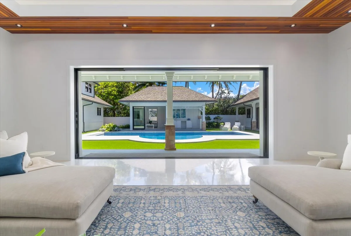 A bright living room opens onto a courtyard with a swimming pool.
