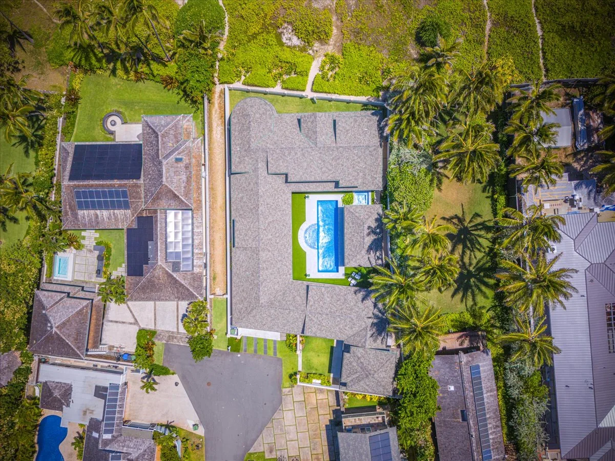 Aerial view of a residential property with a swimming pool and surrounding greenery.