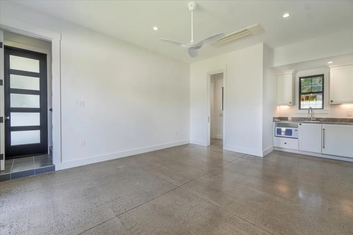 A bright open room connects to a compact kitchen, with polished concrete flooring.