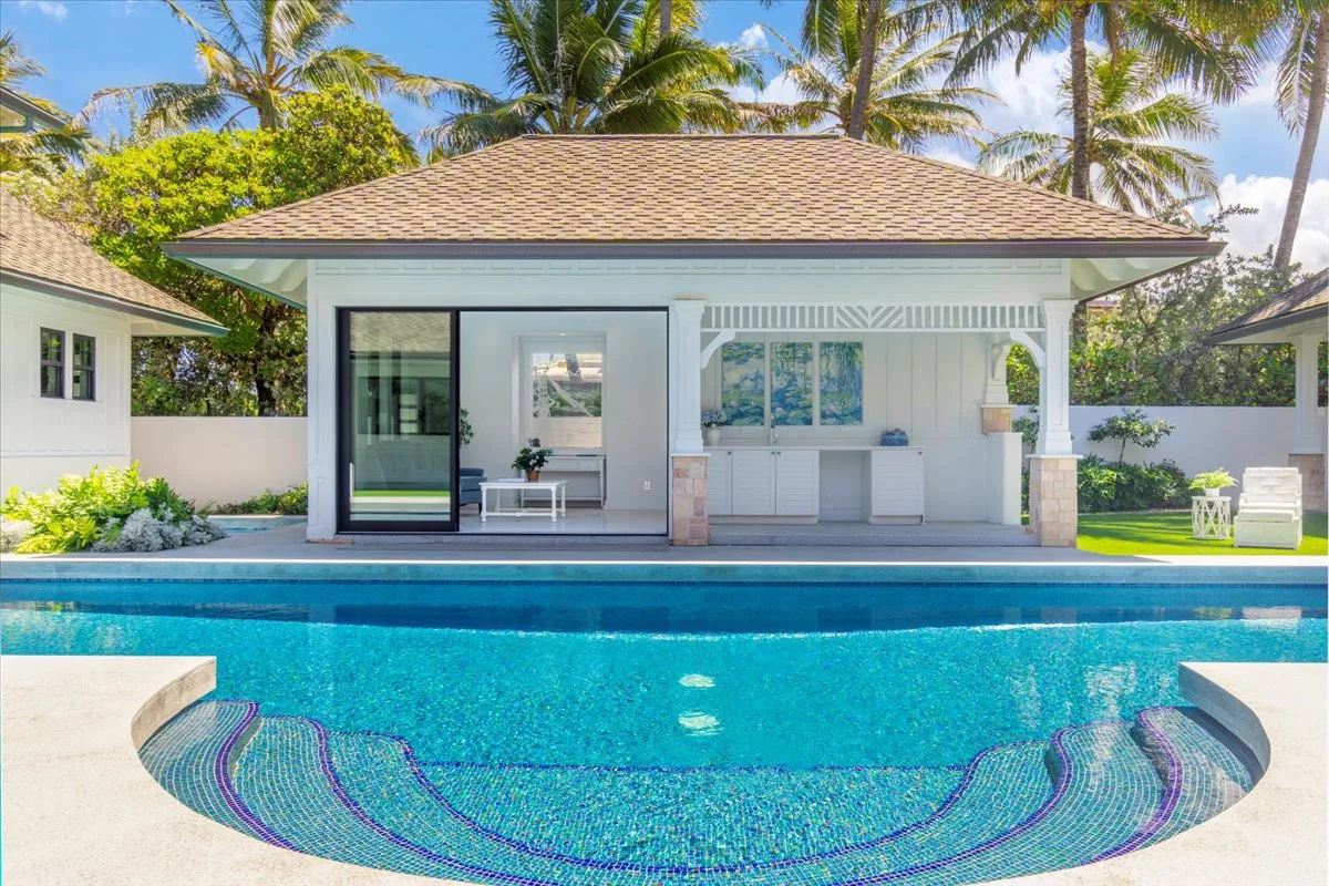 A swimming pool in front of a covered outdoor seating area.