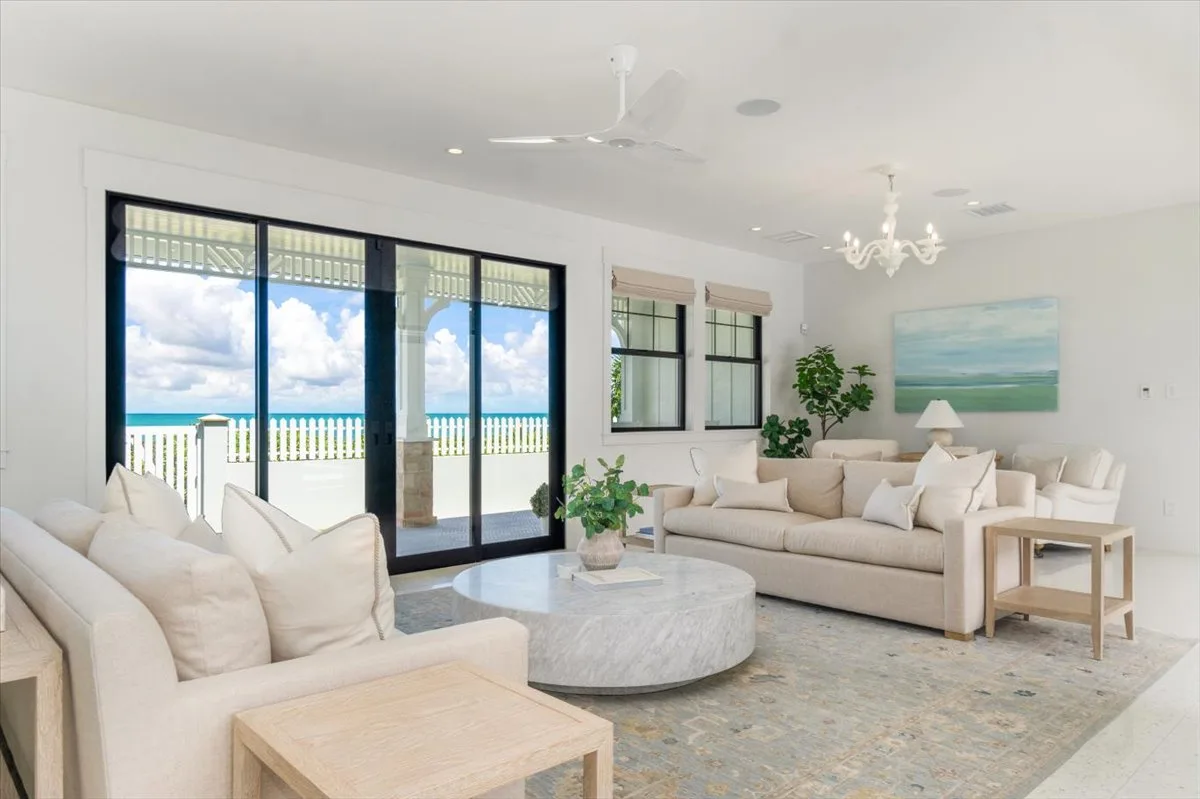 A bright living room with seating beside large glass doors overlooking the ocean.