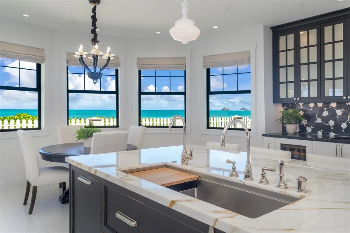 A bright kitchen with a large island, sink, and windows overlooking the water.