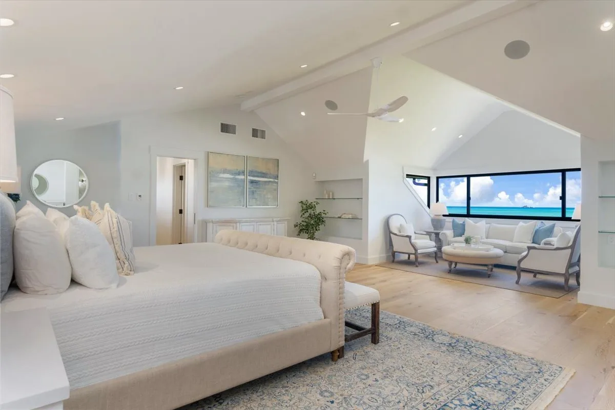 A bright bedroom opens onto a sitting area with large windows.