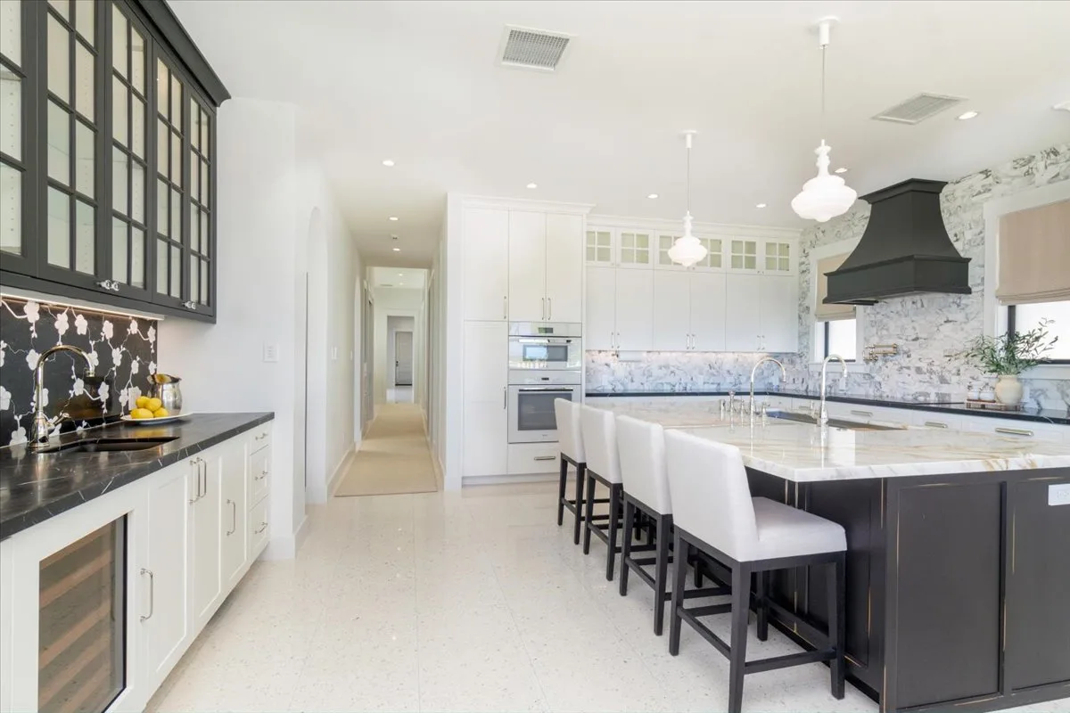A bright kitchen with a large island and a row of stools.