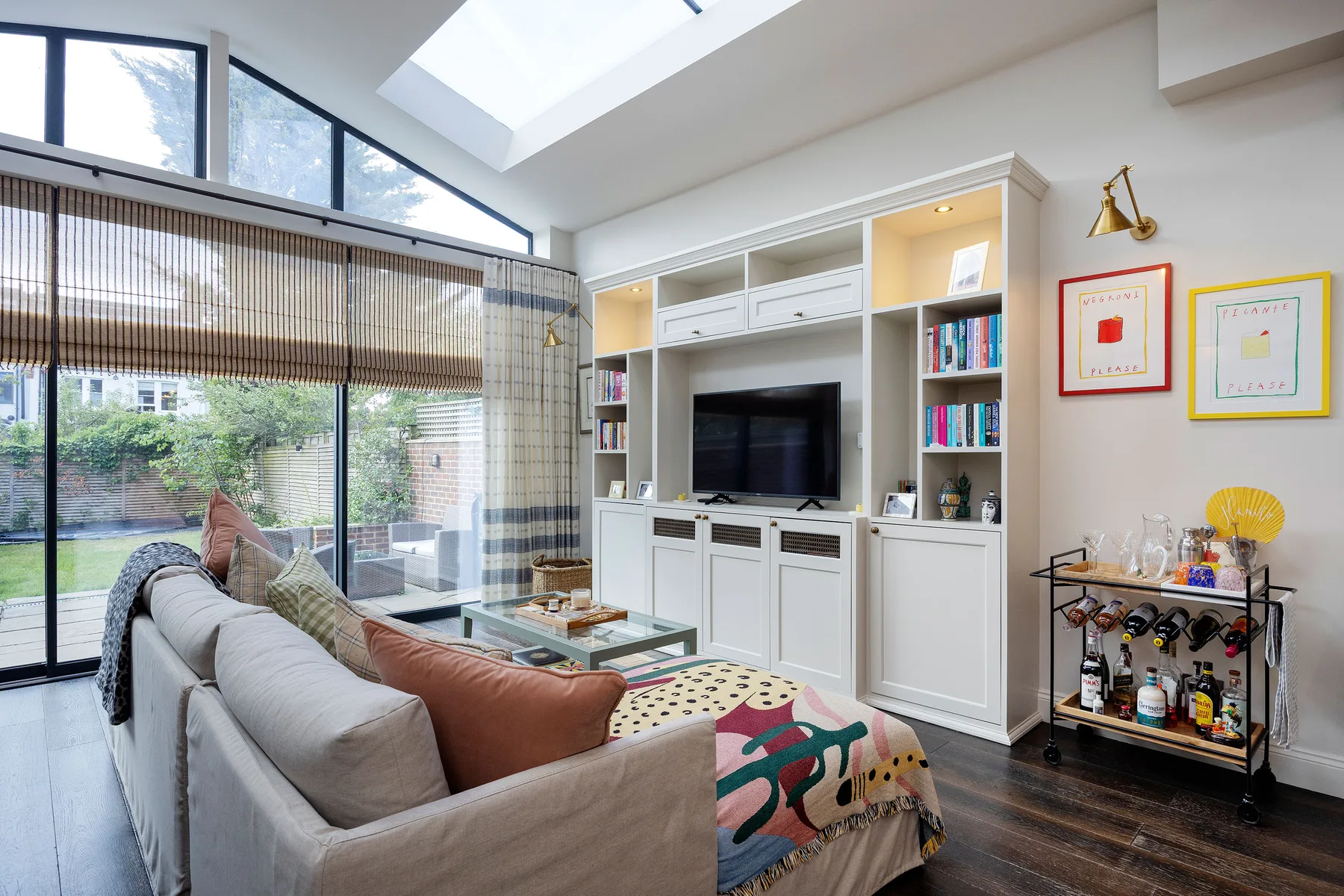 Una sala luminosa con un sofá frente a un mueble empotrado para televisión.