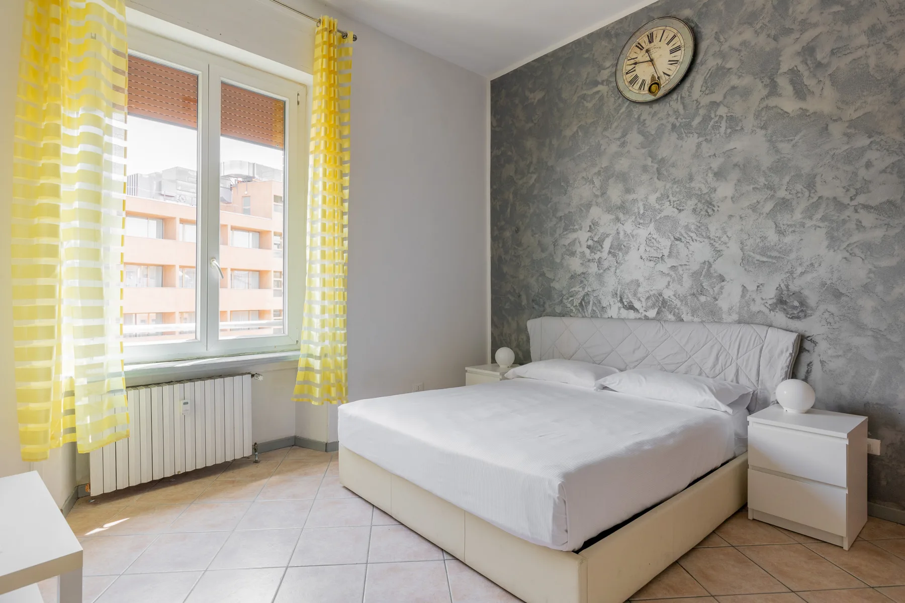Un dormitorio con una cama, cortinas amarillas y un reloj de pared.