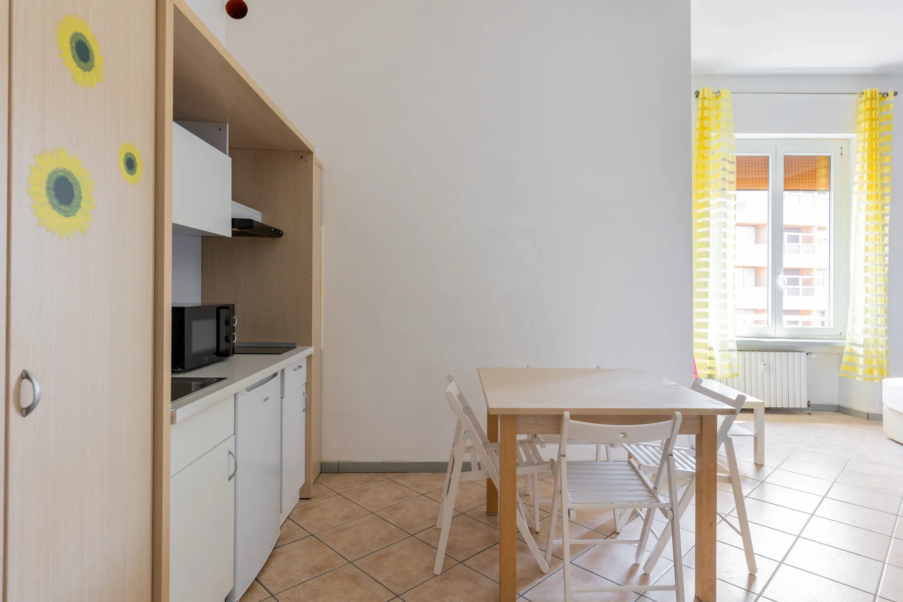 Un comedor con una mesa y sillas junto a una cocina pequeña.