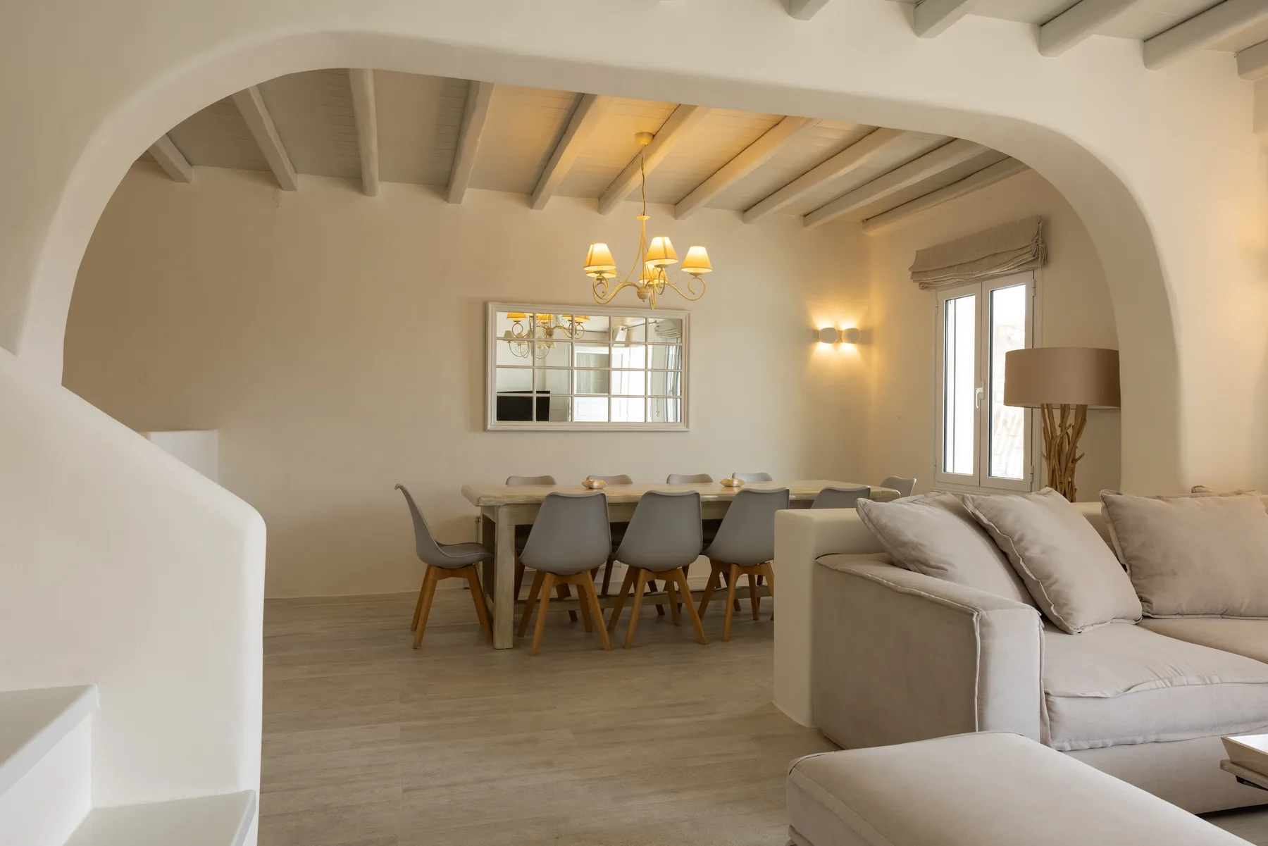 A living and dining area with seating and a table beneath exposed ceiling beams.
