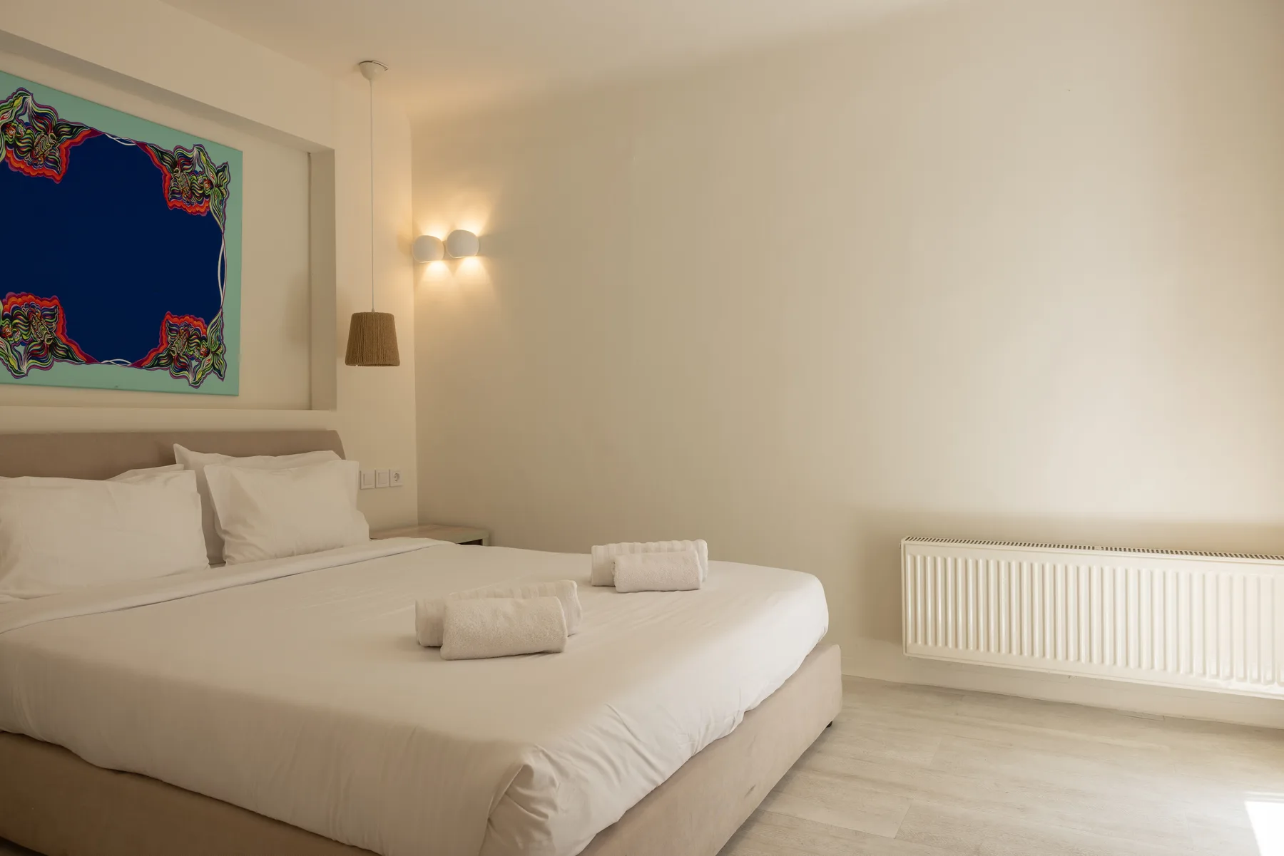 A bedroom with a large bed and a radiator beneath the window.