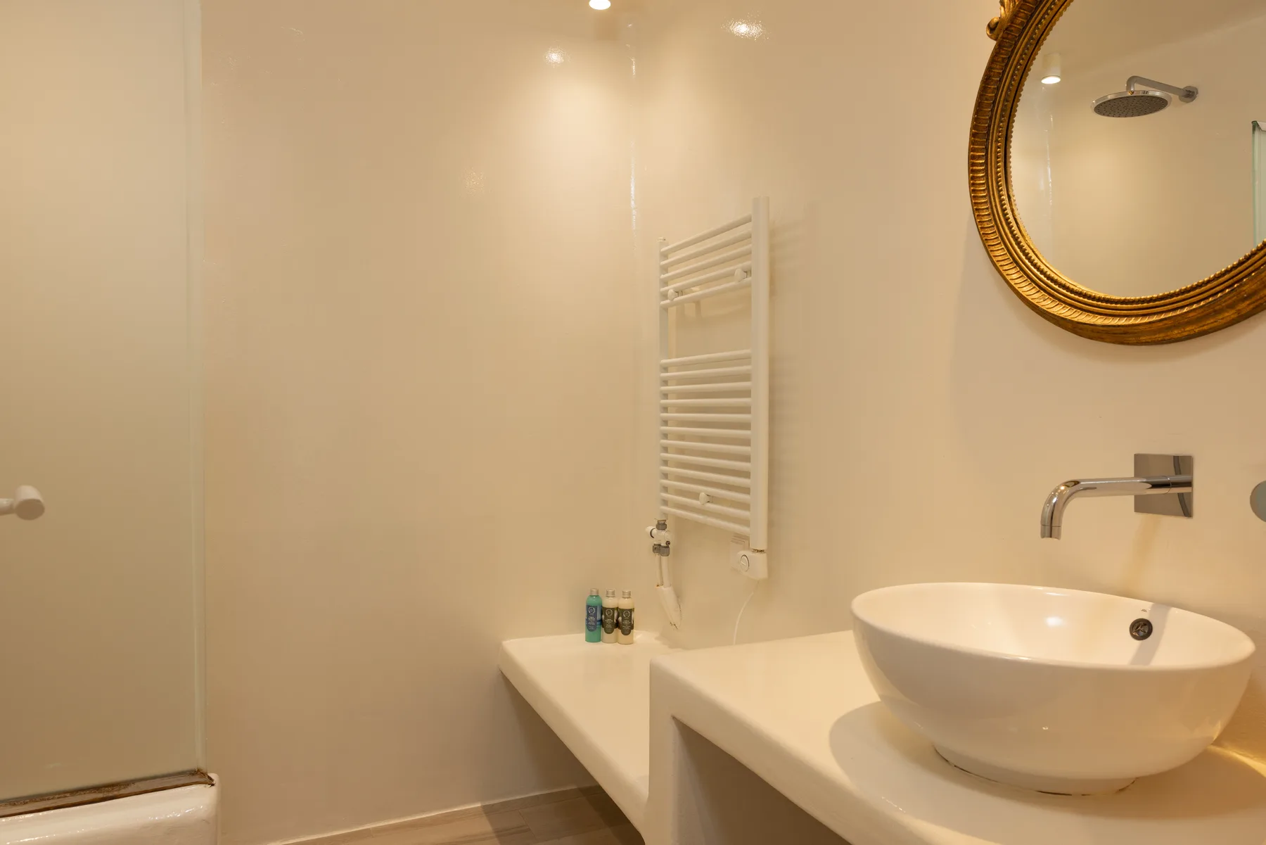 A bathroom with a white vessel sink and wall-mounted towel warmer.