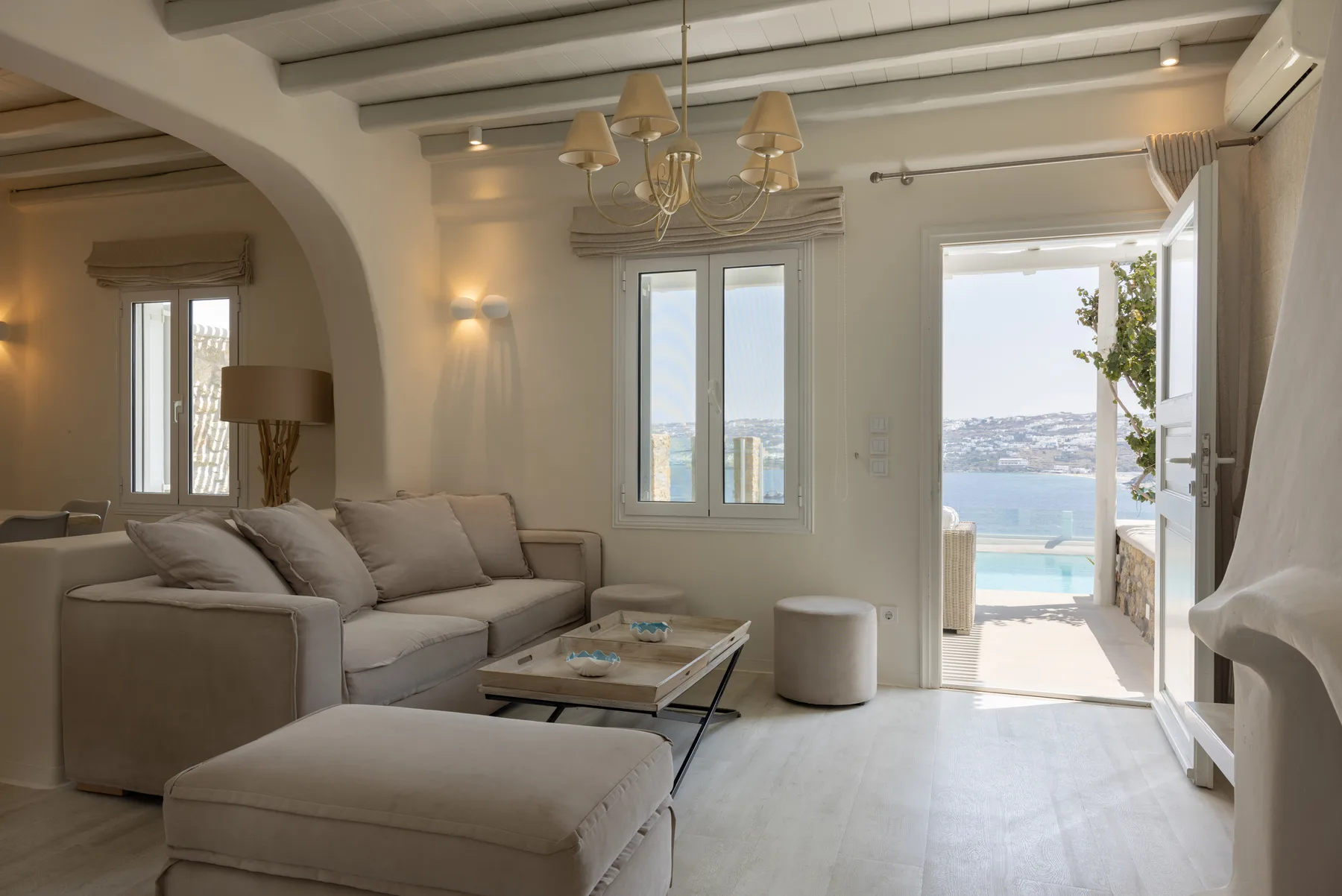 A bright living room with seating and an open doorway to a balcony.