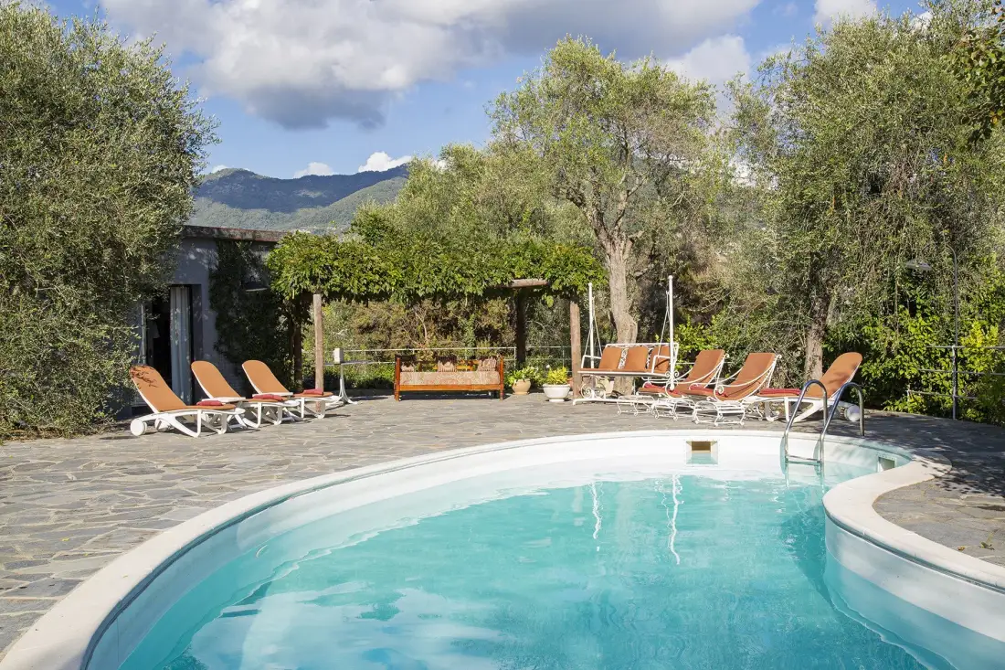 Una piscina al aire libre con asientos reclinables y árboles alrededor del patio.